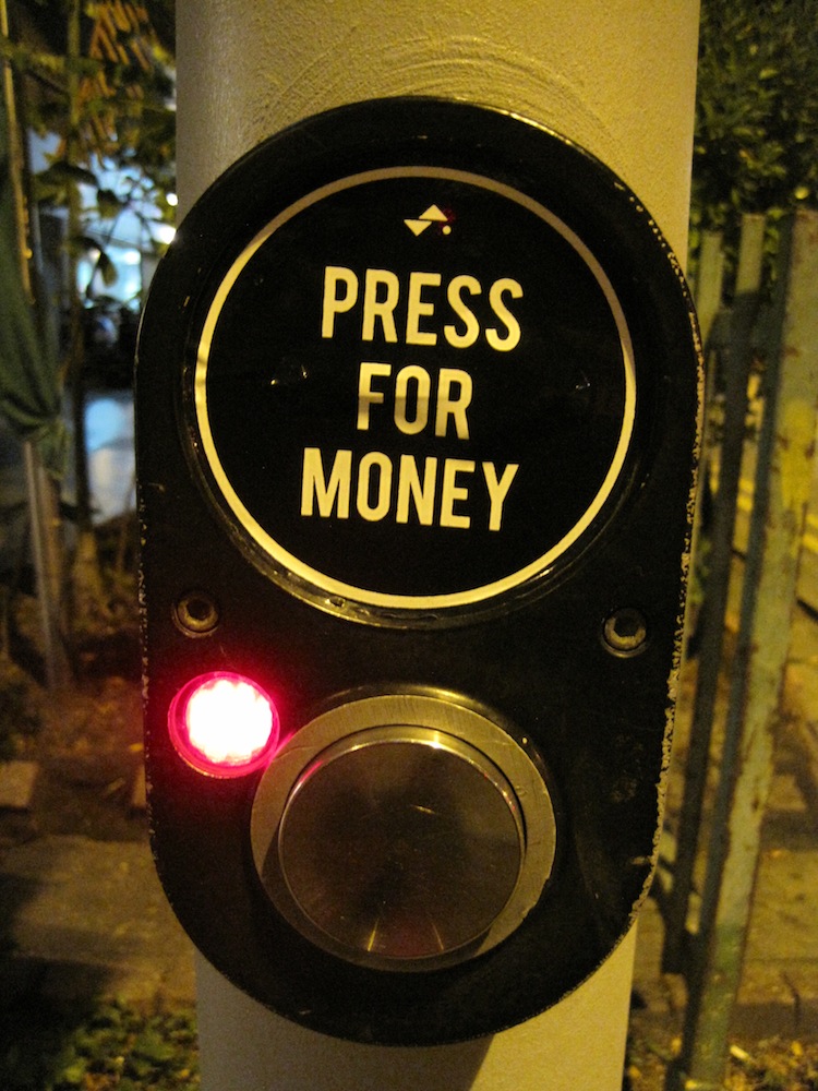 "Press for money" sticker on a crosswalk button in Singapore.
